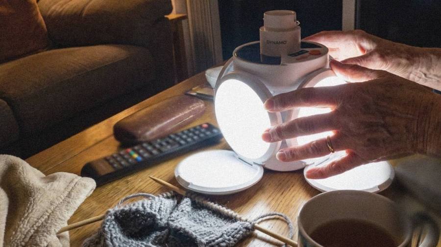 Ältere Hände falten eine leuchtende LED-Lampe auf einem Wohnzimmertisch auseinander